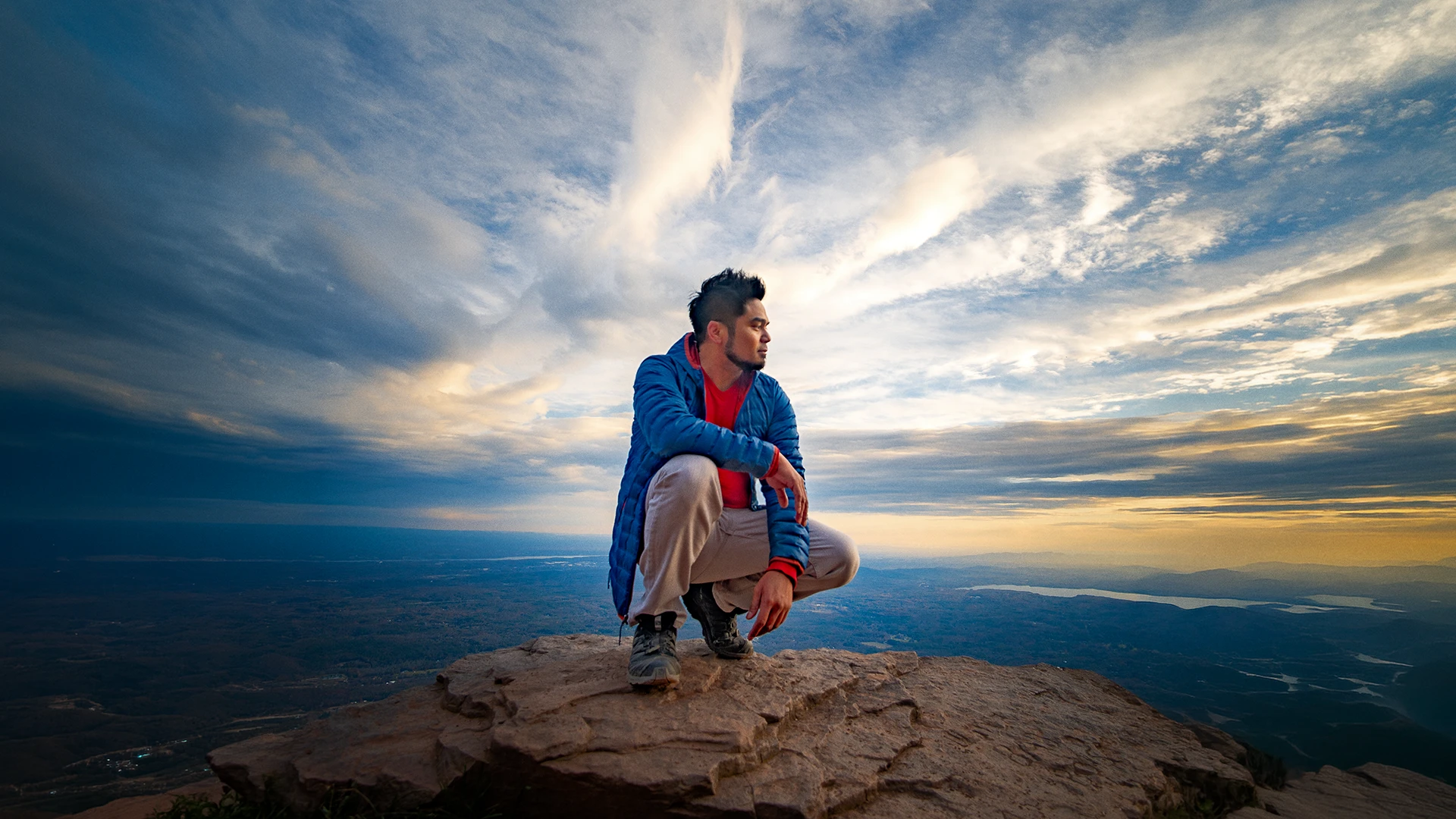 Jerome Mabini sitting on a mountain overlook at sunset